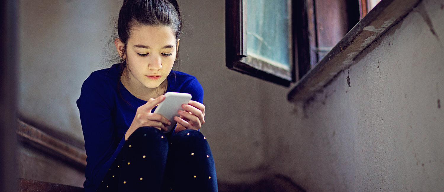  Young girl on phone looking like she could be using an anonymous app like Sarahah. 