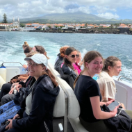 teenage girls sitting on a small speedboat with historic port in the background