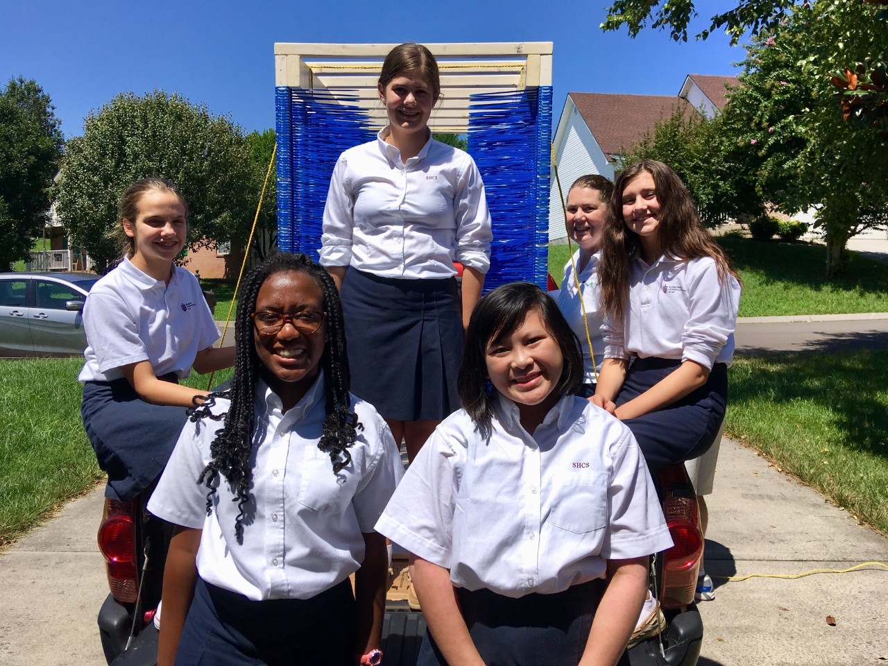 six girls posing on the back of a truck with the zipper